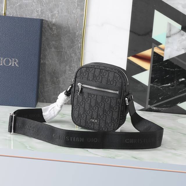470 Dior 这款信使包是本季新品，精巧实用，是日常的理想良伴。采用米色和黑色 Oblique 印花面料精心制作，饰以黑色粒面牛皮革细节。拉链隔层和正面口袋
