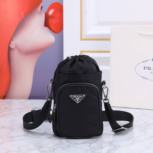 270 回货手机壳包67860 这款手机包采用创新性Re-Nylon再生尼龙打造，展现充满现代感的都市风范。可调式尼龙织带肩带和束绳开合呈现别致特色。正面标志和