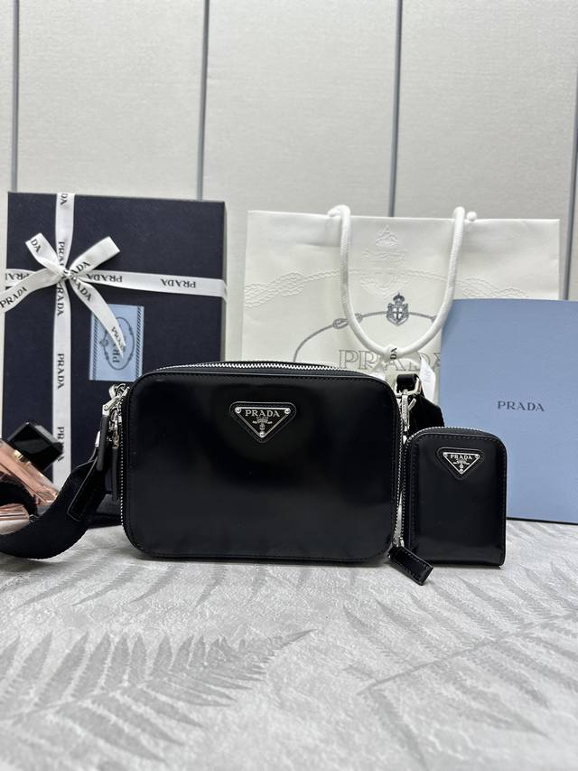 新款邮差包二合一包2Vh070漆皮。 这款现代风范的Brique手袋勾勒简约的线条，搭载可拆卸可调式尼龙带肩带和可拆卸小包，塑造轻盈百搭的风格。所选的复古亮面皮