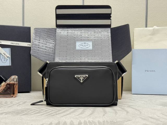 新款腰包2Vh156平纹皮，这款简约而百搭的腰包 胸包采用进口小牛皮，呈现科技感细节现代魅力。再生尼龙调节肩带，配顶级金属插扣和外部拉链式口袋，背面小口袋，内部