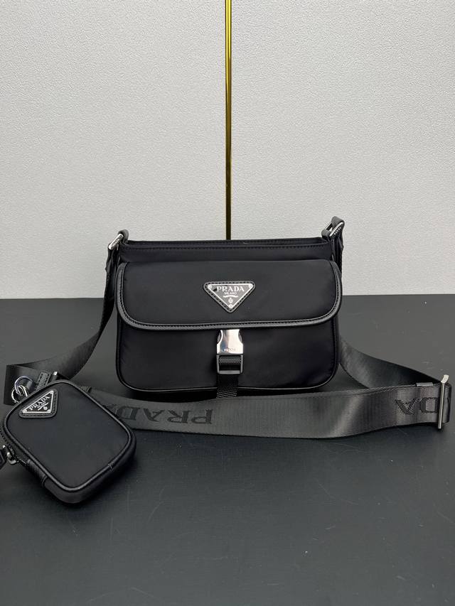 新款邮差包2Vh133 这款单肩包配有正面翻盖，采用标志性的Saffiano皮革和Re-Nylon再生尼龙材质打造。再生尼龙纱线Econyl通过提纯海洋塑料、渔