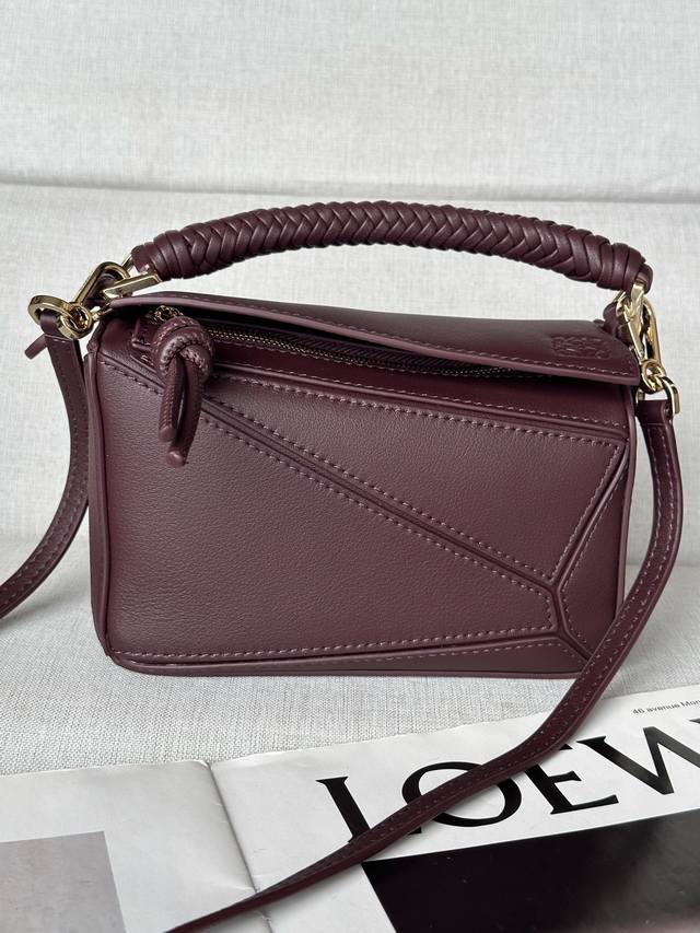 原厂皮 迷你光滑牛皮革 Puzzle 手袋 Puzzle 以别具一格的几何线条勾勒长方体造型。此迷你版本采用光滑牛皮革制成，配有编织纳帕羊皮革提手和绳结拉链头。