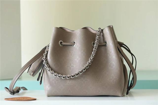 顶级原厂 此款配有零钱包的 Bella 水桶包由 Mahina 牛皮革制成，平纹 Lv 与 Monogram 花卉图案周围环绕 60,000 多个特制镂孔。同色