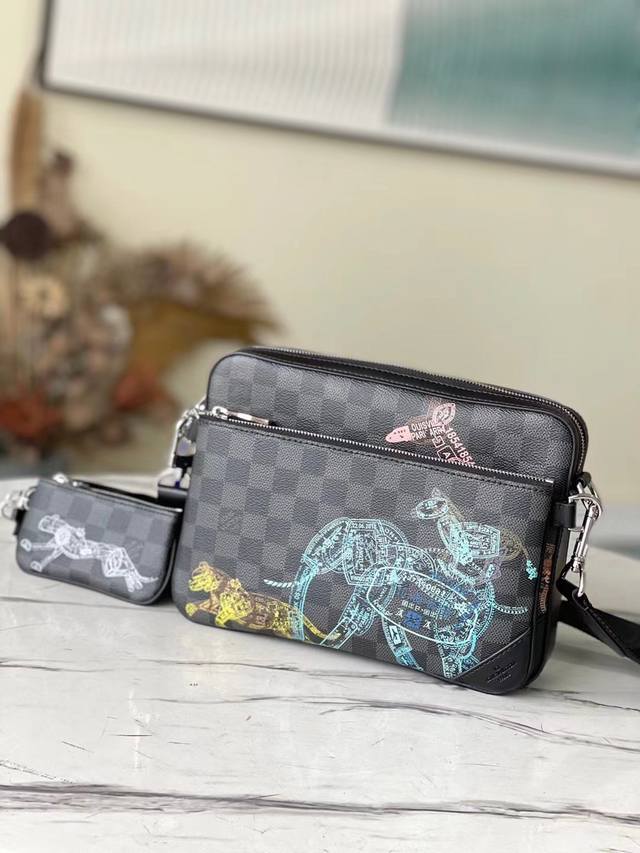 顶级原厂 N 40 本款 Trio 邮差包于 Damier Graphite 帆布表面描绘野生动物群像，近观可见其由恰似护照印章的图案组成。拉链主隔层、可拆卸小