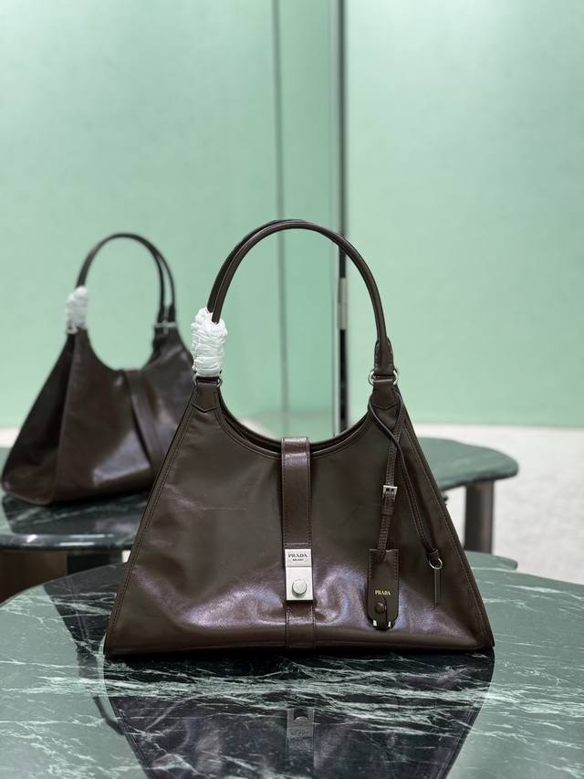 大号 春夏最新走秀款，几何线条与精致匠心细节，是这款柔美体量手袋的亮点所在。梯形廓形配以纤长手提柄，亦可作为单肩包轻松肩背。竖向锁扣的设计灵感源自档案库，皮革镜