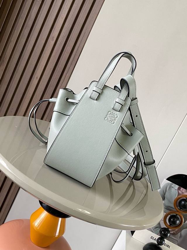 迷你柔软粒面牛皮革 Hammock 抽绳袋带有柔软侧面抽绳包身的多功能手袋可释放侧面抽绳来改变形状。环状带子可以使手袋有多种佩戴方式这个迷你版本采用柔软粒面牛皮