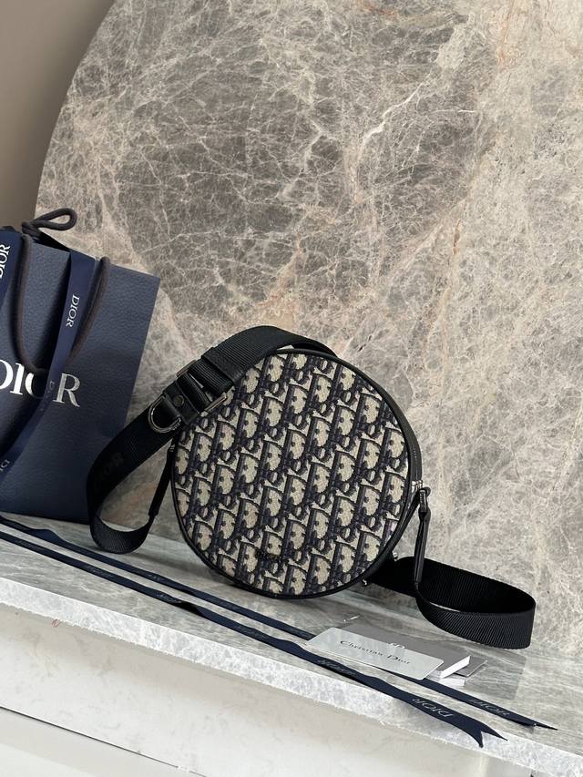 p 这款 Dior Yoyo 拉链信使包是二零二五夏季男装系列新品，时尚实用。圆形款式，采用米色和黑色 Oblique 印花面料等材质精心制作，饰以黑色粒面牛皮