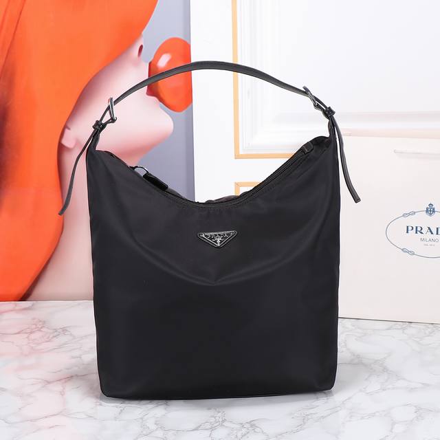 回货托特包这款托特包采用创新的再生尼龙面料打造，设计简约时尚。包身配有精美的Saffiano皮革提手，饰以标志性的涂珐琅三角形金属徽标，传递品牌讯息。空间容量大