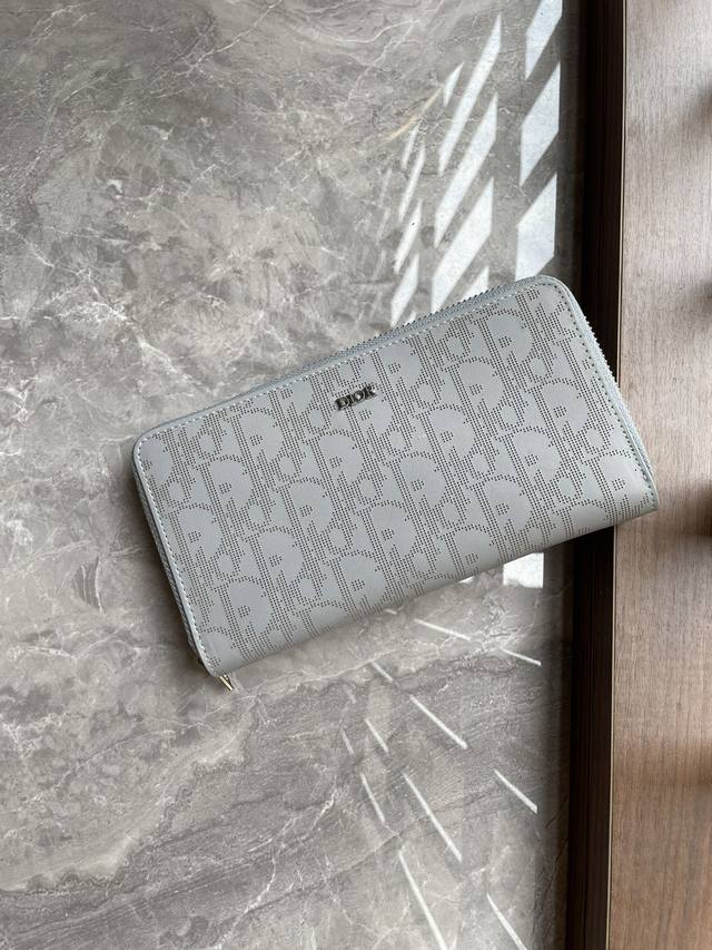 Di0R 灰色Oblique Galaxy印花效果皮革，采用镂空的光滑牛皮革搭配反光里料中间的拉链隔层可放置硬币，两个现金隔层和12个卡位提供充足的收纳空间。长