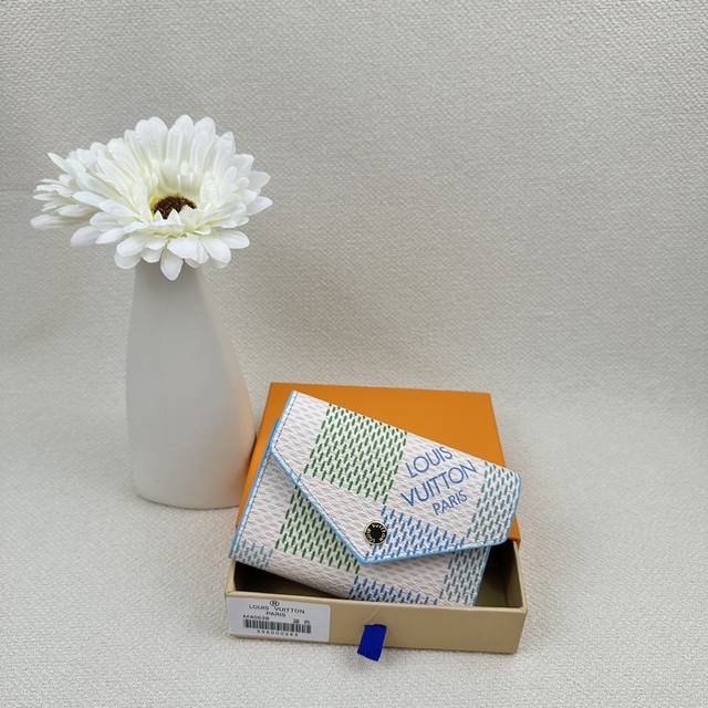 M40638 此款Damiericious”用充满魅力的粉彩风格重新诠释了Damiervicetine画布。以施有刻印的金领的按扣开合的圆形翻盖为特征的小钱包，