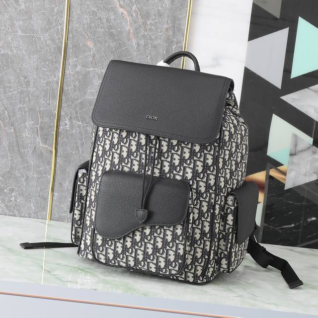 这款马鞍双肩背包采用时尚的原创设计，突显马鞍风格。采用米色和黑色 Oblique 印花提花面料精心制作，饰以黑色粒面牛皮革细节，正面点缀以“Dior”标志。宽敞