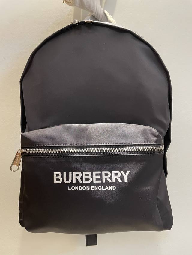 Burberry新款尼龙双肩包，印有焕新的品牌标识Logo，搭配平滑皮革边饰，肩带饰有Burberry字母提花精仿微标。底部使用牛皮材质，双向拉链开合，亮泽金属
