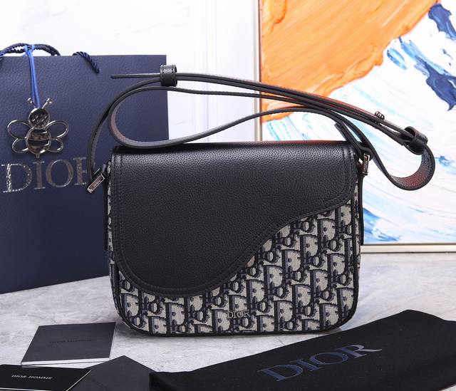 型号：93322 顶级原单 这款迷你马鞍信使包精巧时尚。采用黑色粒面牛皮革精心制作，饰以翻盖和“Dior”标志，突显马鞍包的精致魅力。内部隔层宽敞，搭配贴袋，可