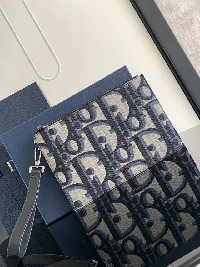 这款 A5 手拿包是一款优雅简约的配饰。采用米色和黑色超大 Oblique 印花面料精心制作，重新演绎品牌经典图案，正面点缀以 Dior 标志，搭配粒面牛皮革饰