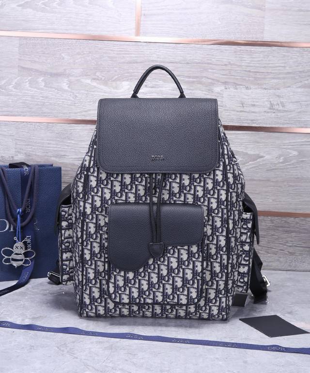 顶级原单 顶级原单 这款马鞍双肩背包采用时尚的原创设计，突显马鞍风格。采用米色和黑色 Oblique 印花提花面料精心制作，饰以黑色粒面牛皮革细节，正面点缀以“