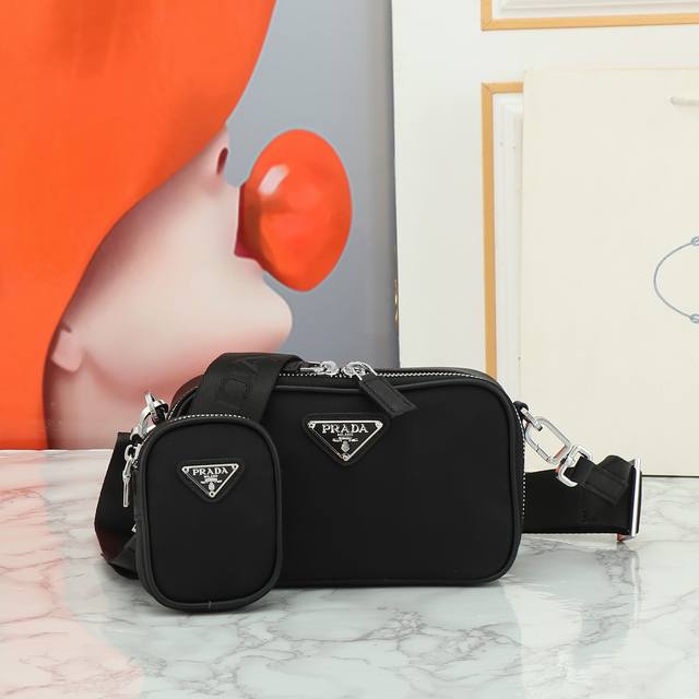 回货专柜最新款到货标志性的Prada男士手袋于新系列中重新诠释，选材再生尼龙和Saffiano皮革塑造简约线条和结构式廓形，特色鲜明。手袋配肩带，并以徽标装点，