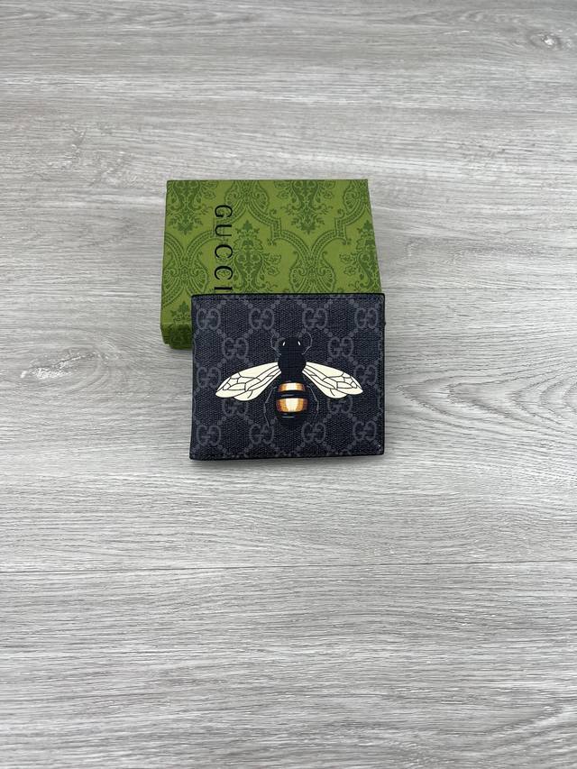 gucci 饰Gg蜜蜂印花钱包。Gucci小件皮革配饰突破设计界限，不断以个性方式焕新演绎经典单品。这款男士钱包将经典Gg Supreme帆布与黑色Gg配件匠心