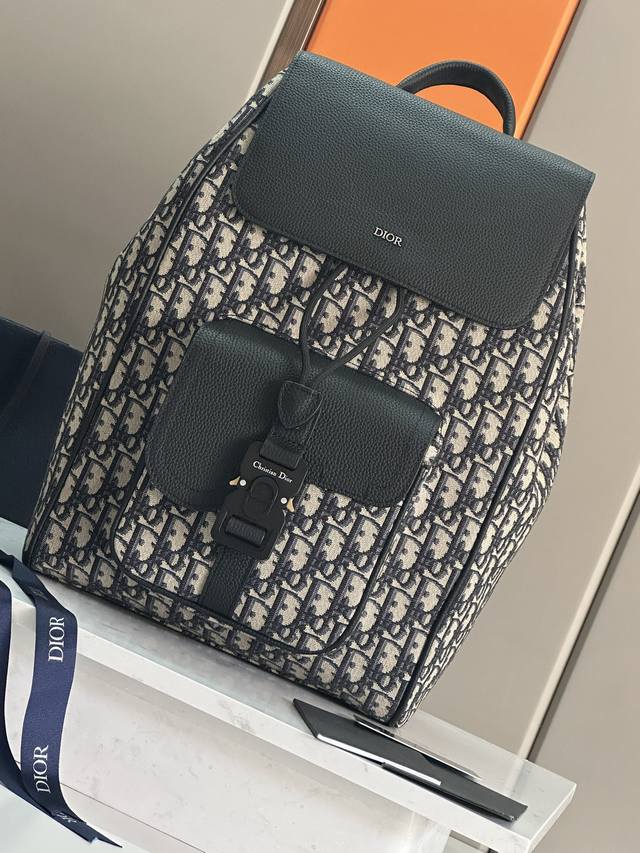 这款马鞍双肩背包是二零二四秋季男装系列新品，采用时尚的原创设计，突显马鞍风格。采用米色和黑色 Oblique 印花面料精心制作，饰以黑色粒面牛皮革细节，正面点缀