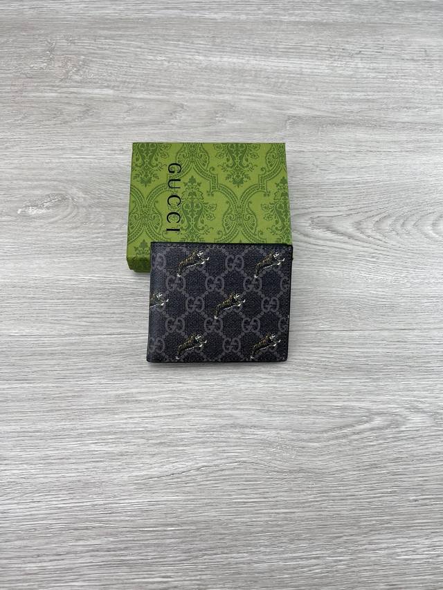 gucci 饰Gg虎印花钱包。Gucci小件皮革配饰突破设计界限，不断以个性方式焕新演绎经典单品。这款男士钱包将经典Gg Supreme帆布与黑色Gg配件匠心糅
