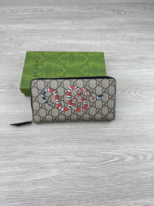 gucci 饰Gg珊瑚蛇细节拉链钱包。Gucci小件皮革配饰突破设计界限，不断以个性方式焕新演绎经典单品。这款男士钱包将经典Gg Supreme帆布与黑色Gg配