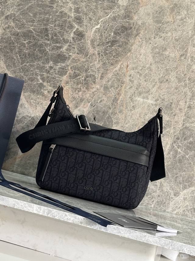 顶级原单这款 Rider Soft 水饺包是二零二五秋季男装系列新品，兼具实用功能与时尚设计。采用米色和黑色 Oblique 印花面料等材质精心制作，饰以黑色粒