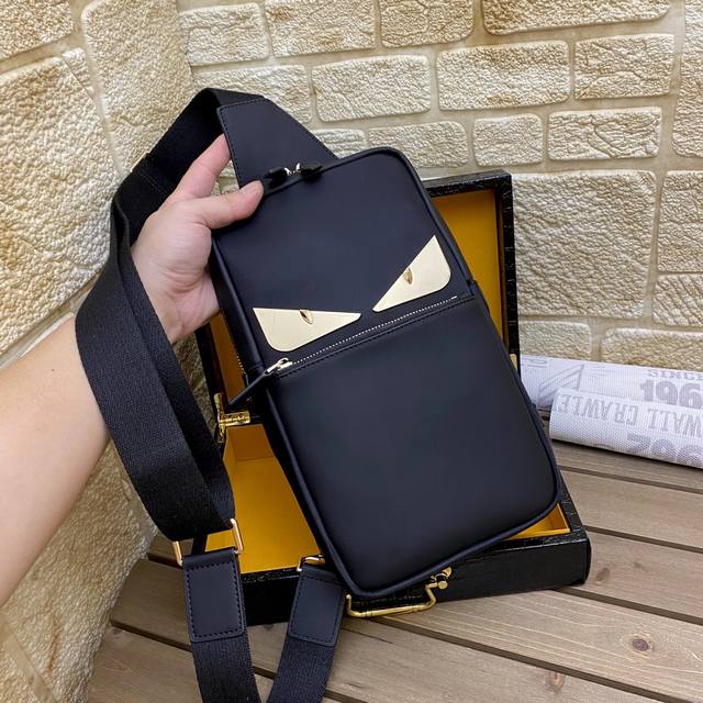 p爆 型号：2336金色 芬迪Fendi小怪兽长方形背包男士斜挎胸包，以黑色科技布料制成，缀以同色系皮革。旅行体验极佳的包袋，设有两个隔层和实用的尼龙肩带，长度