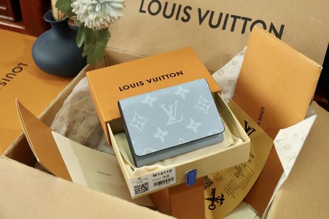 m14118 蓝 见证 Monogram 帆布与 Taga 皮革的春日邂逅，以牛皮革内衬、卡片夹层和口袋彰显功能考量，搭配后部外袋。精巧构型可轻松收入口袋。