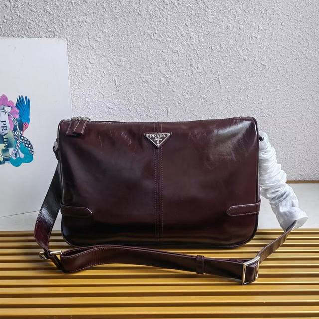 顶级原单 新品油腊皮2Vh187邮差包这款单肩包选用柔软而富有光泽的油腊皮革精心制作，流畅简约的廓形搭配精致细节，饰以独特的三角形徽标，时尚百搭。可调式皮革肩带