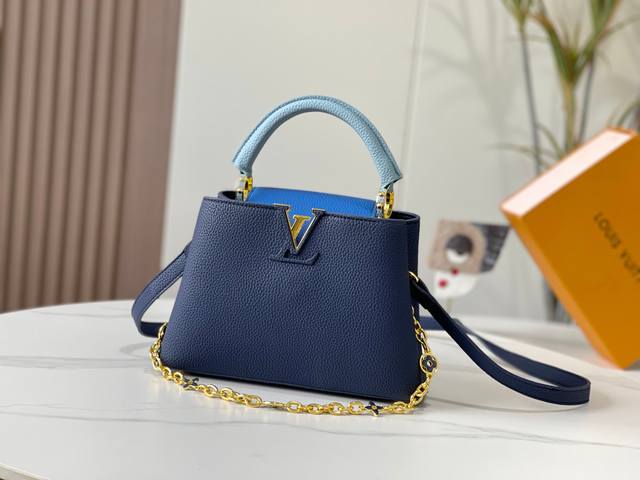 升级版 M20844宝蓝色花卉三拼 本款 Capucines Bb 手袋取材 Taurillon 皮革，隐约映现同一色彩的浓淡变化，令经典构型更为瞩目，搭配珐琅