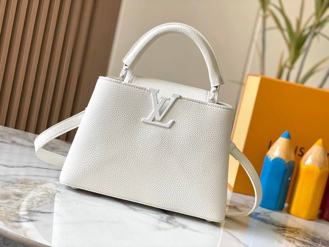 升级版 M25256白色本款Capucines大号手袋为哑光Taurillon牛皮革搭配金属件，令经典设计展露利落风范。翻盖提供外置或内收两式风尚，齐整内里设有