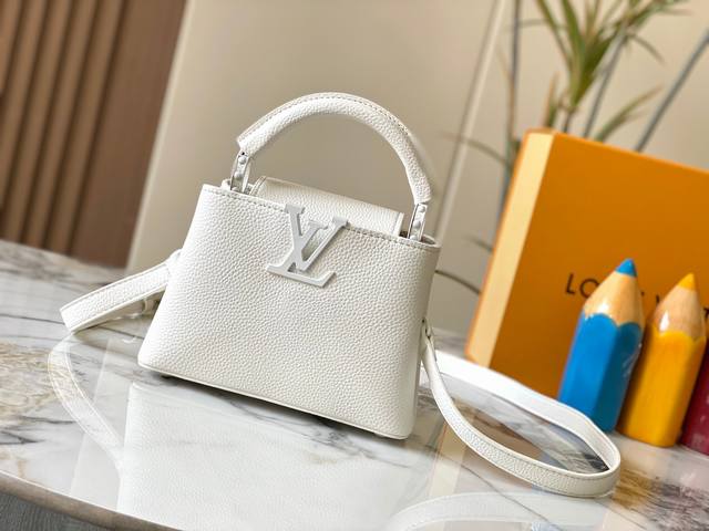 升级版 M25255白色本款Capucines小号手袋为哑光Taurillon牛皮革搭配金属件，令经典设计展露利落风范。翻盖提供外置或内收两式风尚，齐整内里设有