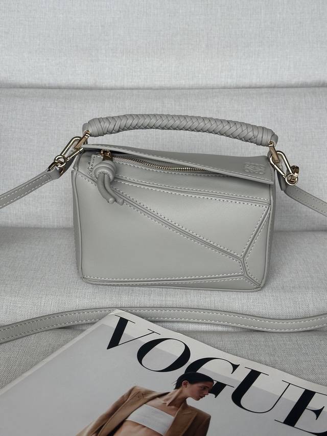 原厂皮 贝壳灰色 迷你光滑牛皮革 Puzzle 手袋 Puzzle 以别具一格的几何线条勾勒长方体造型。此迷你版本采用光滑牛皮革制成，配有编织纳帕羊皮革提手和绳