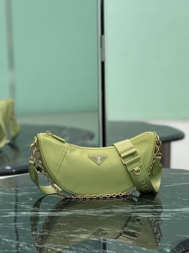 新品月牙包 这款Re-Nylon手袋采用再生尼龙面料制作，精致而百搭，融合档案库造型与实用的当代风格。半月廓形，搭配可拆卸运动风肩带与优雅的链条手提柄，背法多样