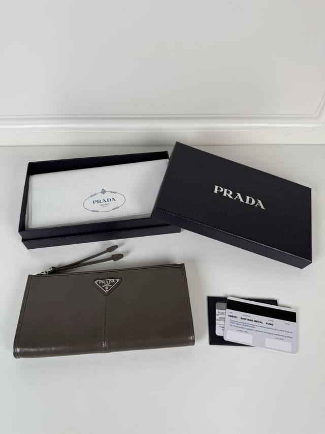 P家男女通用小袋包，这款小袋简约精致，采用进口油腊皮制作，三角形金属徽标，拉链开合。型号：1Mb051，尺寸20Cm*10Cm 2个卡位，1个皮革衬里