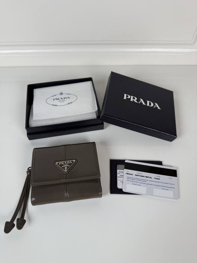 P家女士油腊皮短夹,原单品质,型号1Mh043,四个卡位插口,一个票据隔层,两个证件袋,一个外部口袋,内部翻盖式零钱袋一个,尺寸10X8.5Cm。 P家女士油腊皮短夹,原单品质,型号1Mh043,四个卡位插口,一个票据隔层,两个证件袋,一个外部口袋,内部翻盖式零钱袋一个,尺寸10X8.5Cm。