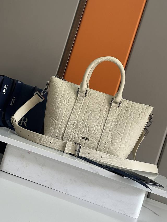 正品级 这款 Weekender 25 手袋设计经典高雅。Dior Gravity 印花效果皮革采用压花工艺将经典图案精致地呈现于黑色牛皮革之上，饰以 Dior