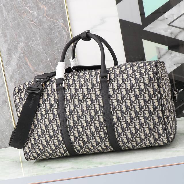 这款 Dior Lingot 50 手袋是本季新品，实用而优雅，别具一格。采用米色和黑色 Oblique 印花面料精心制作，搭配黑色粒面牛皮革细节提升格调，正面