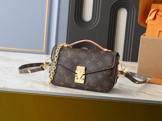 M46279 本款Lv邮差包出小号 East West MéTis 手袋采用时尚肩背书包造型，富有潮流感。小巧包身取材品牌 Monogram 帆布，配有别致的