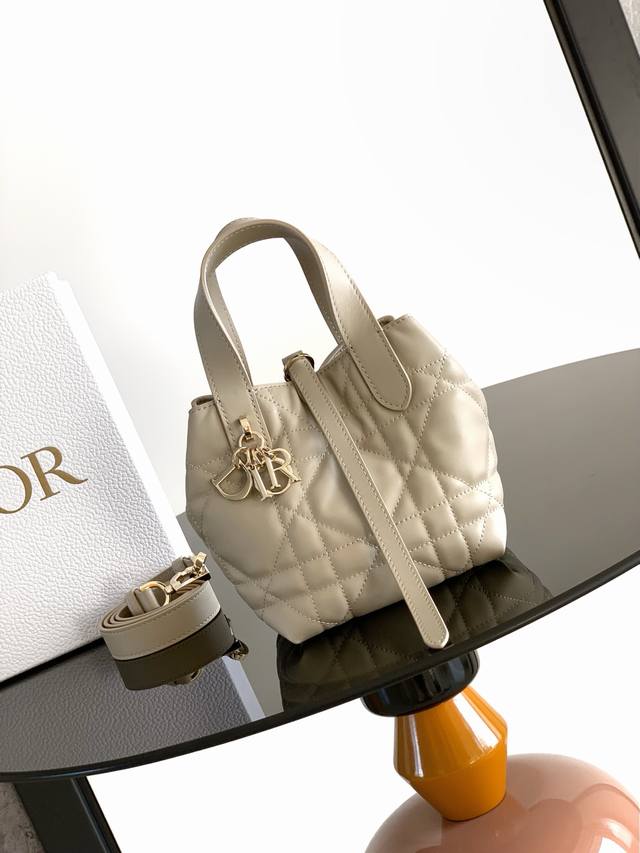 迷你号 这款微型 Dior Toujours 竖版手袋是二零二五秋季成衣系列新品，时尚实用。采用胭脂米色牛皮革精心制作，饰以超大藤格纹缉面线，宽敞的内部隔层可收