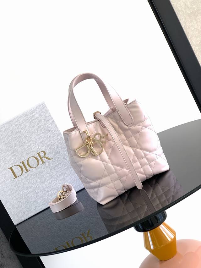 这款 Dior Toujours 竖版手袋时尚实用，别具一格。采用粉色牛皮革精心制作，饰以超大藤格纹缉面线，宽敞的内部隔层可收纳各种日常用品。设有纤细皮革系带开