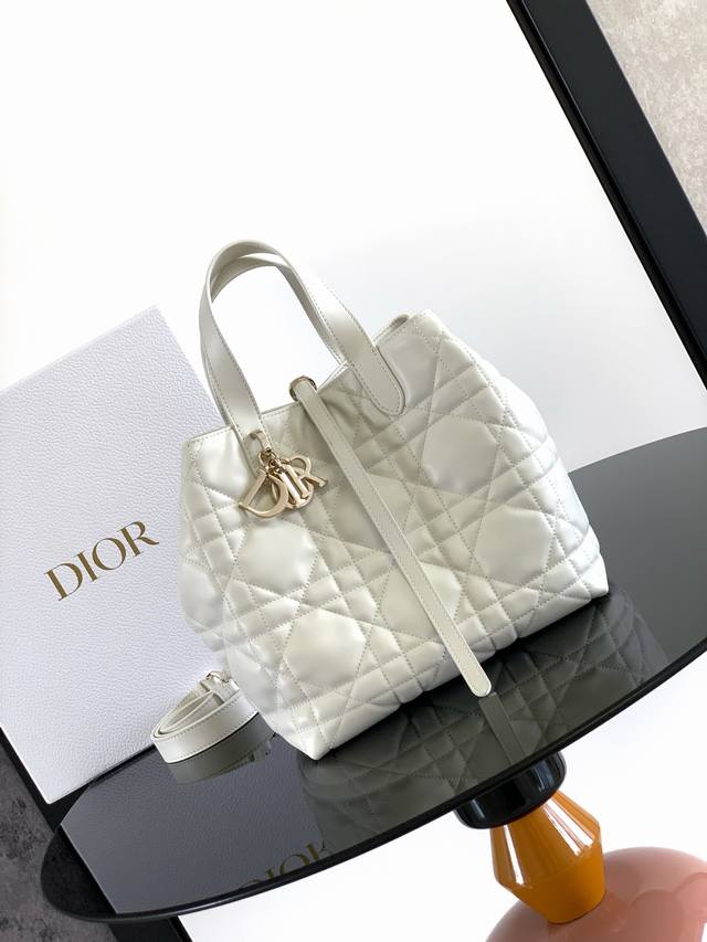 这款 Dior Toujours 竖版手袋时尚实用，别具一格。采用白色牛皮革精心制作，饰以超大藤格纹缉面线，宽敞的内部隔层可收纳各种日常用品。设有纤细皮革系带开