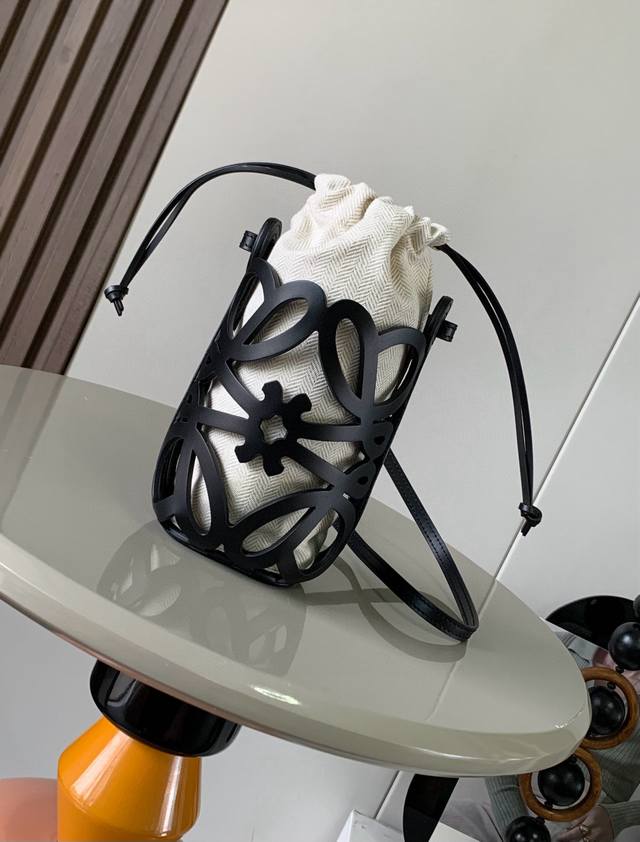 经典牛皮革和帆布 Anagram镂空小袋这款多功能的斜挎小袋采用Anagram 图案镂空牛皮革制成并配有绳带和人字纹棉质帆布抽绳内袋个头小小的巨能装适合出游休闲