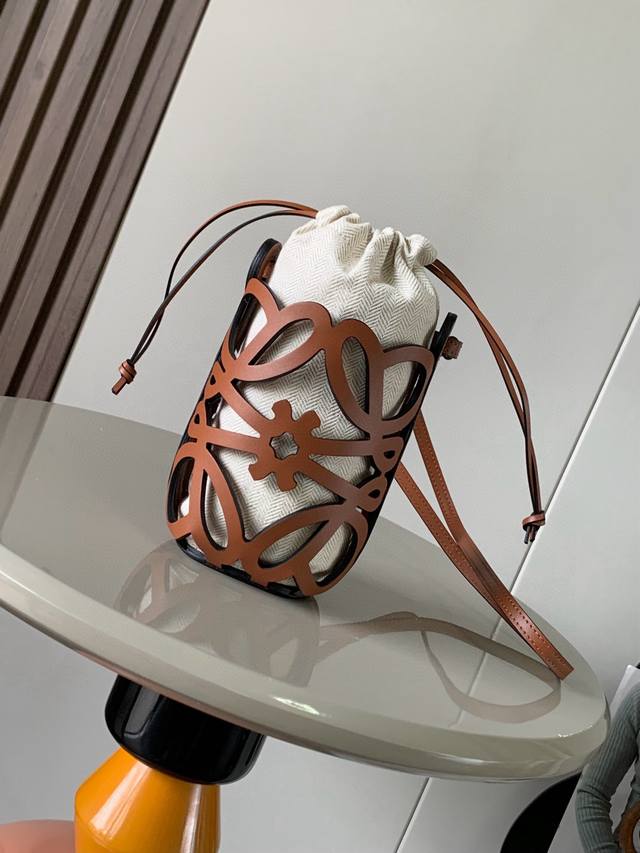 经典牛皮革和帆布 Anagram镂空小袋这款多功能的斜挎小袋采用Anagram 图案镂空牛皮革制成并配有绳带和人字纹棉质帆布抽绳内袋个头小小的巨能装适合出游休闲