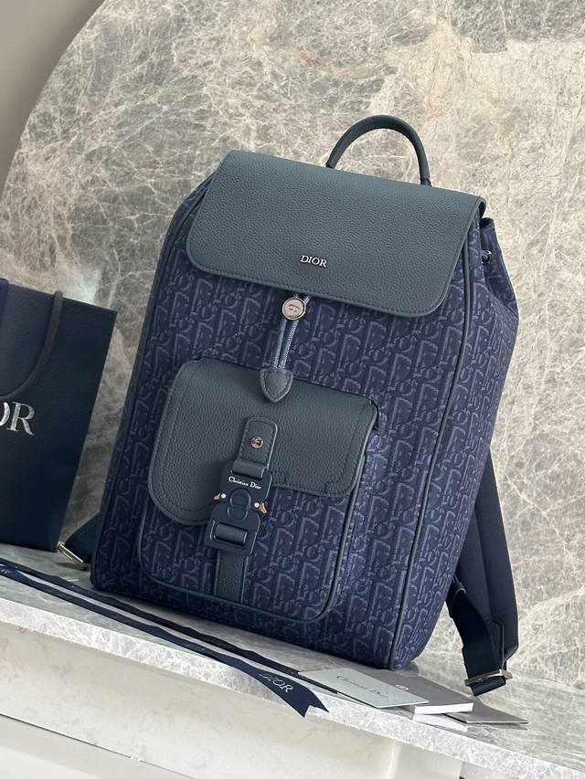 这款马鞍双肩背包是二零二四秋季男装系列新品，采用时尚的原创设计，突显马鞍风格。采用米色和黑色 Oblique 印花面料精心制作，饰以黑色粒面牛皮革细节，正面点缀