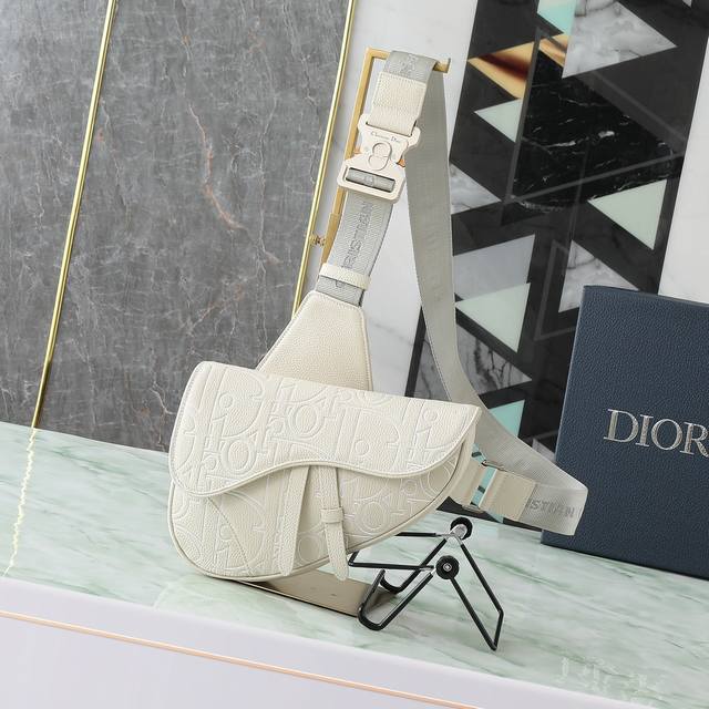 这款马鞍包时尚经典。采用米色Dior Gravity Outline皮革等材质精心制作，这是一种压花粒面牛皮革，饰以3D效果Dior经典图案，彰显图形魅力。搭配