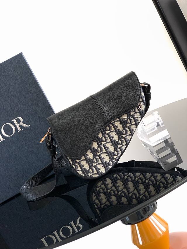 这款马鞍包以现代结构全新演绎经典设计。采用米色和黑色 Oblique 印花面料精心制作，饰以经典的黑色粒面牛皮革磁性翻盖，搭配隐藏式拉链开合。内部设有大号隔层和