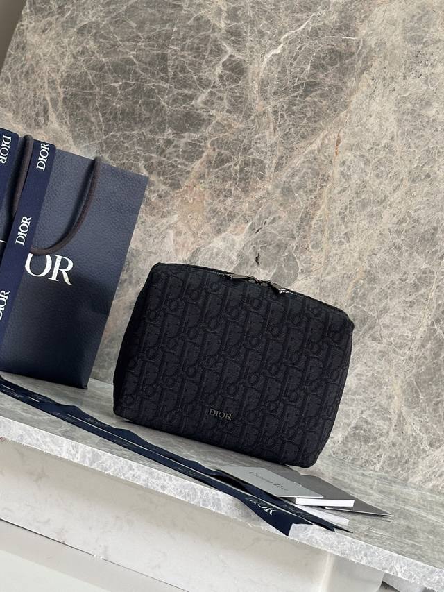 P 这款旅行手拿包实用又时尚。采用米色和黑色Oblique 印花面料等材质精心制作，正面饰以Dior标志提升格调。缝有三角形衬料的设计，宽大的拉链隔层设有三个插