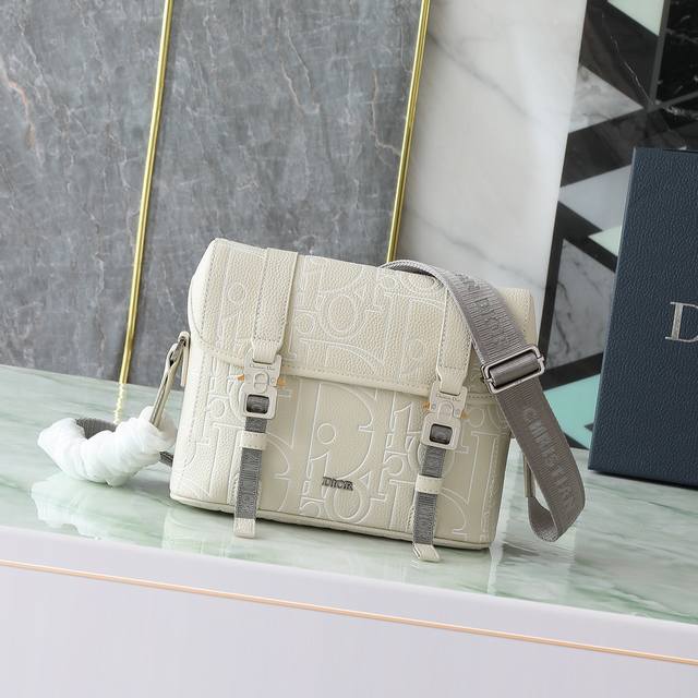 这款翻盖信使包以现代时尚的设计突显Dior的高订精神，进一步丰富 Dior Hit The Road 系列。采用米色Dior Gravity Outline皮革