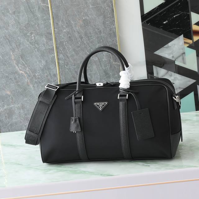 这款Re-Nylon再生尼龙旅行袋饰以精美的Saffiano皮革镶边，呈现充满现代感的优雅魅力。可拆卸肩带便于背携，标志性的金属三角形徽标彰显品牌格调。 为确保