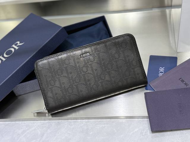 这款长款拉链式钱包低调而不失优雅气质。原单材料精心制作，内部为黑色光滑牛皮革材质。中间的拉链口袋可放置硬币，双层现金隔层和 12 个卡槽提供充足的收纳空间。优雅